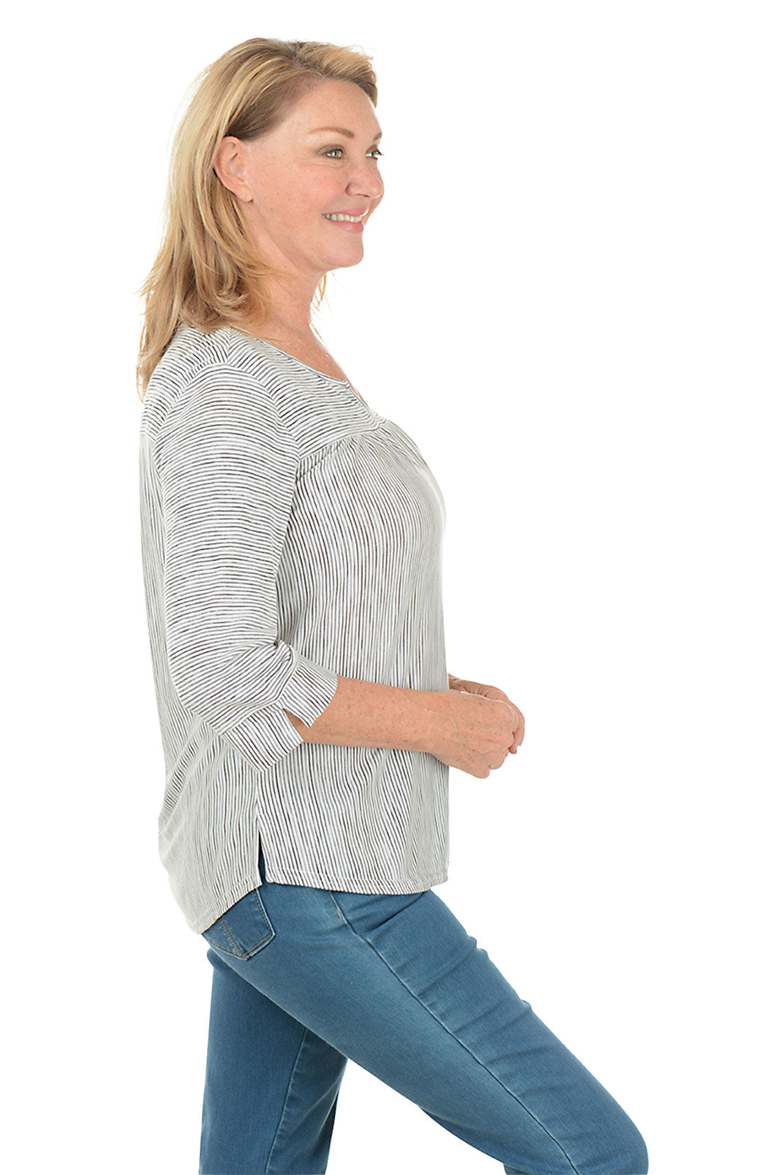 Woman wearing a striped blouse and blue jeans on a white background. Side shot.
