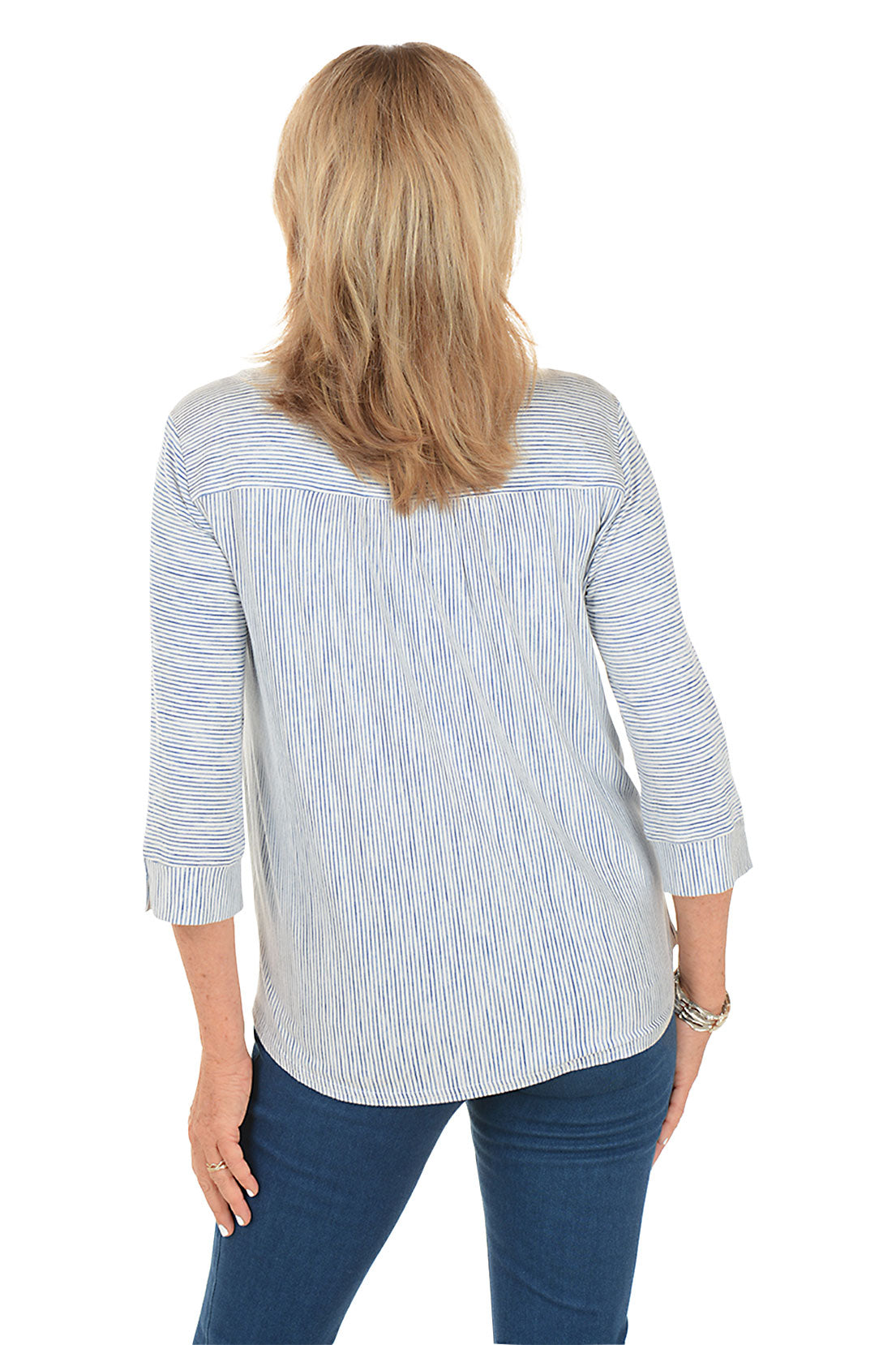 Woman wearing a blue and white striped shirt and blue jeans on a white background. Back shot.
