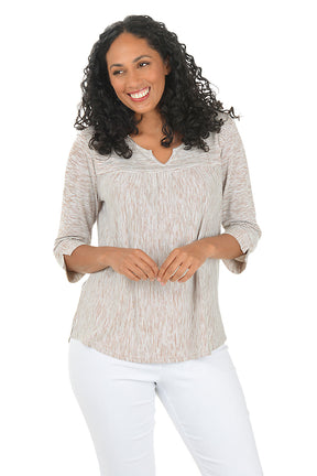 Woman wearing a brown and white striped shirt and blue jeans on a white background.