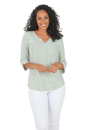 Woman wearing a green and white striped shirt and blue jeans on a white background.