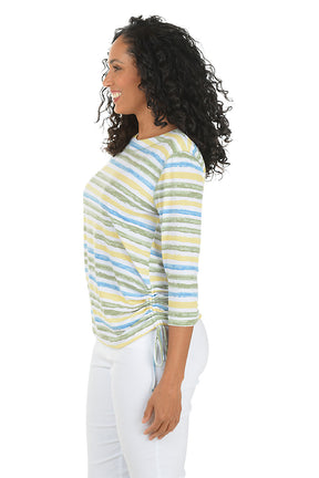 Woman wearing a striped long-sleeve top and white pants on a white background. Side shot.
