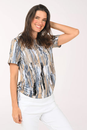 Woman wearing a patterned blouse and white pants on a white background