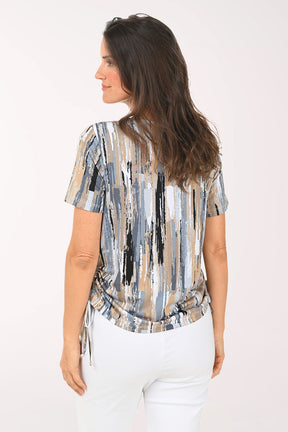 Woman wearing a patterned blouse and white pants on a white background