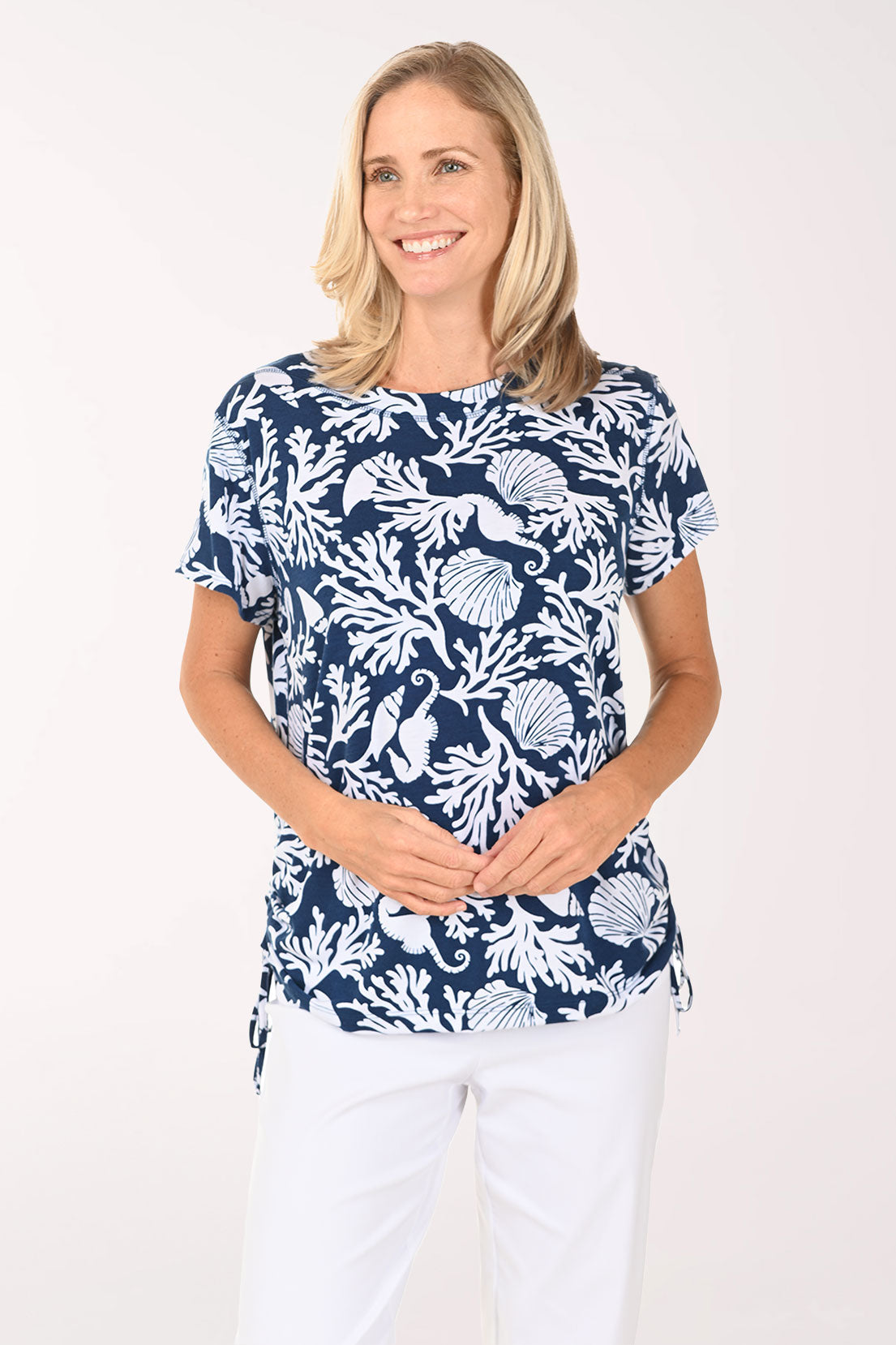 Woman wearing a short sleeve blue shirt with shell and coral details