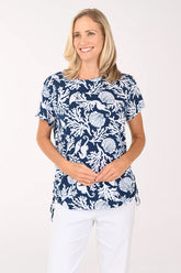 Woman wearing a short sleeve blue shirt with shell and coral details