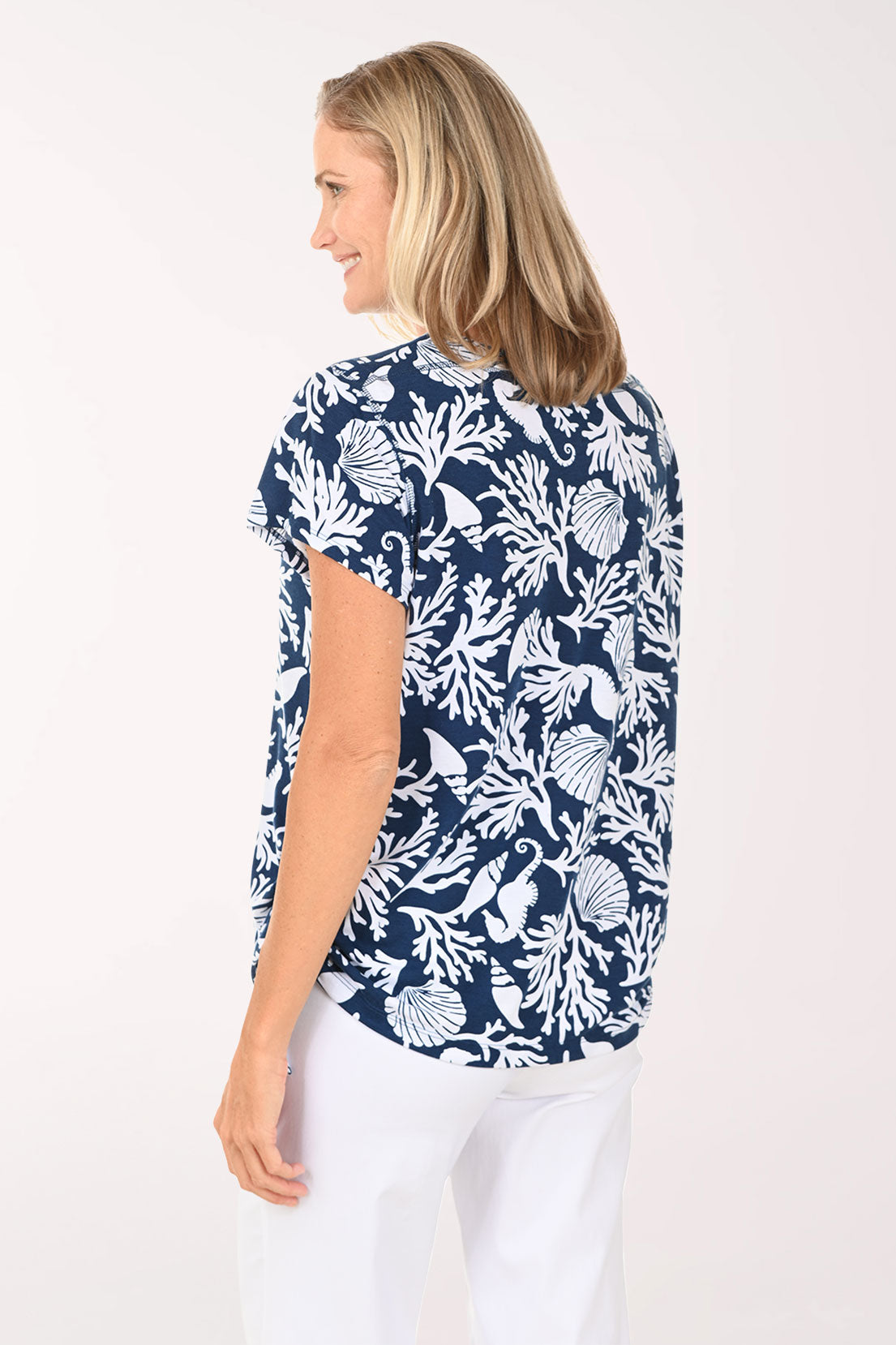 Woman wearing a short sleeve blue shirt with shell and coral details