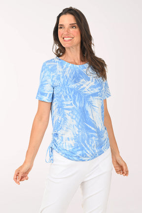 Woman wearing a blue tie-dye shirt and white pants on a white background