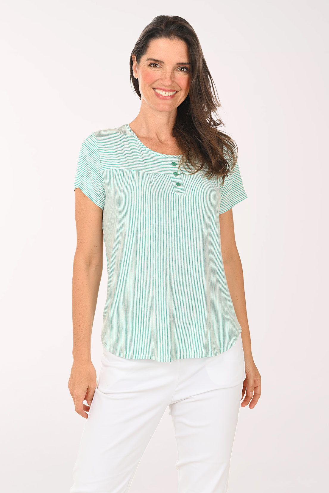 Woman wearing a light green striped shirt and white pants on a white background