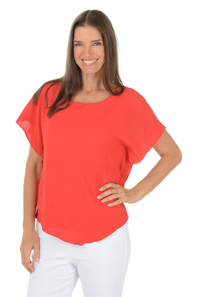 Woman wearing a red blouse and white pants on a white background