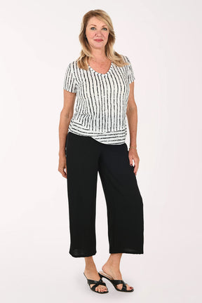 Woman wearing a black and white short sleeve tee and black flared crop pants