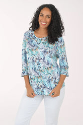 Woman wearing a floral print top and white pants on a white background