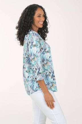 Woman wearing a floral print top and white pants on a white background
