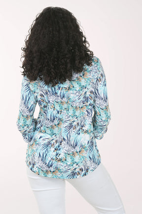 Woman wearing a floral print top and white pants on a white background