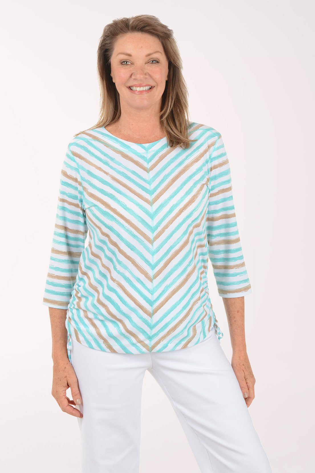 Woman wearing a striped turquoise and beige top with white pants on a white background