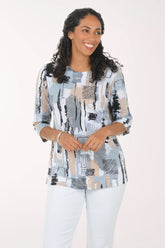 Woman wearing a patterned top and white pants on a white background