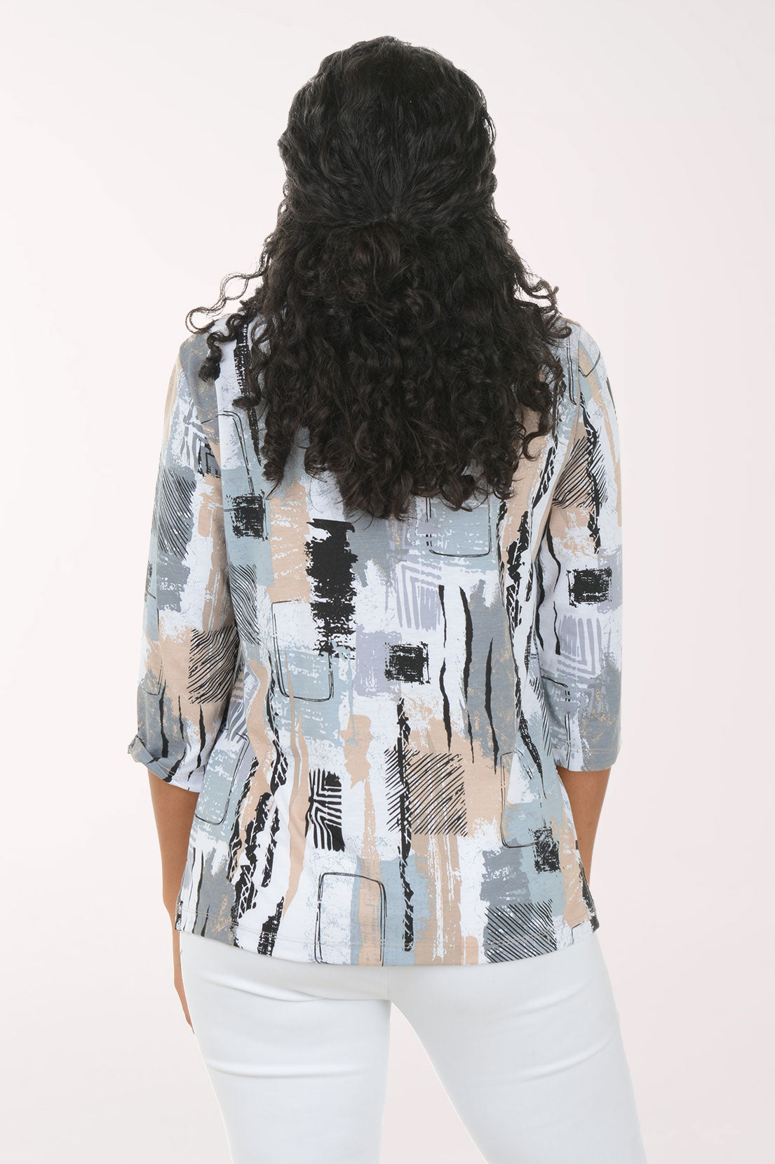 Woman wearing a patterned top and white pants on a white background