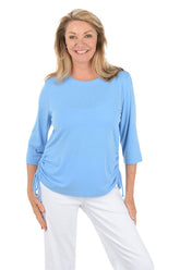 Woman wearing a light blue top and white pants on a white background