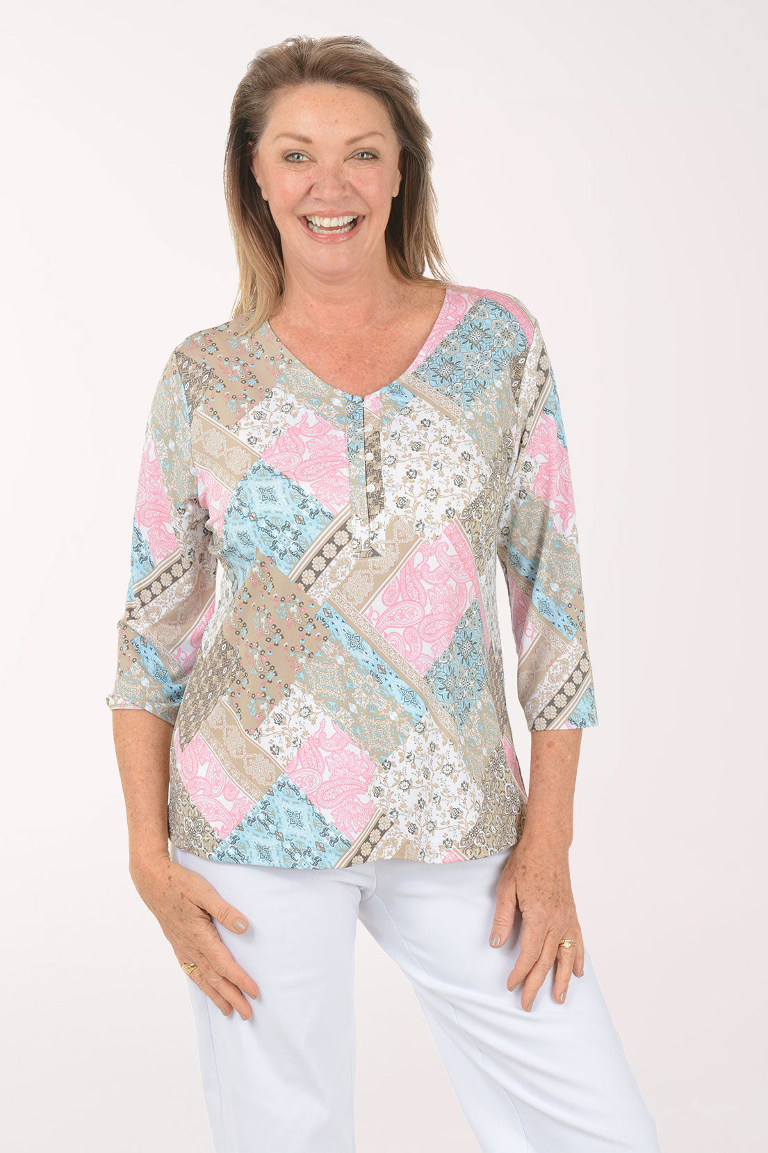 Woman wearing a patterned top with pastel colors on a white background