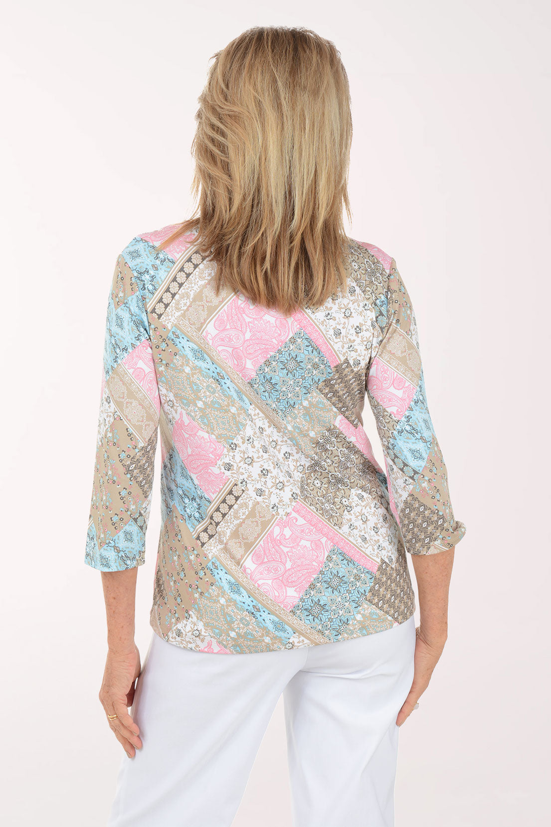 Woman wearing a patterned top with pastel colors on a white background