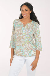 Woman wearing a floral blouse with white pants on a plain background