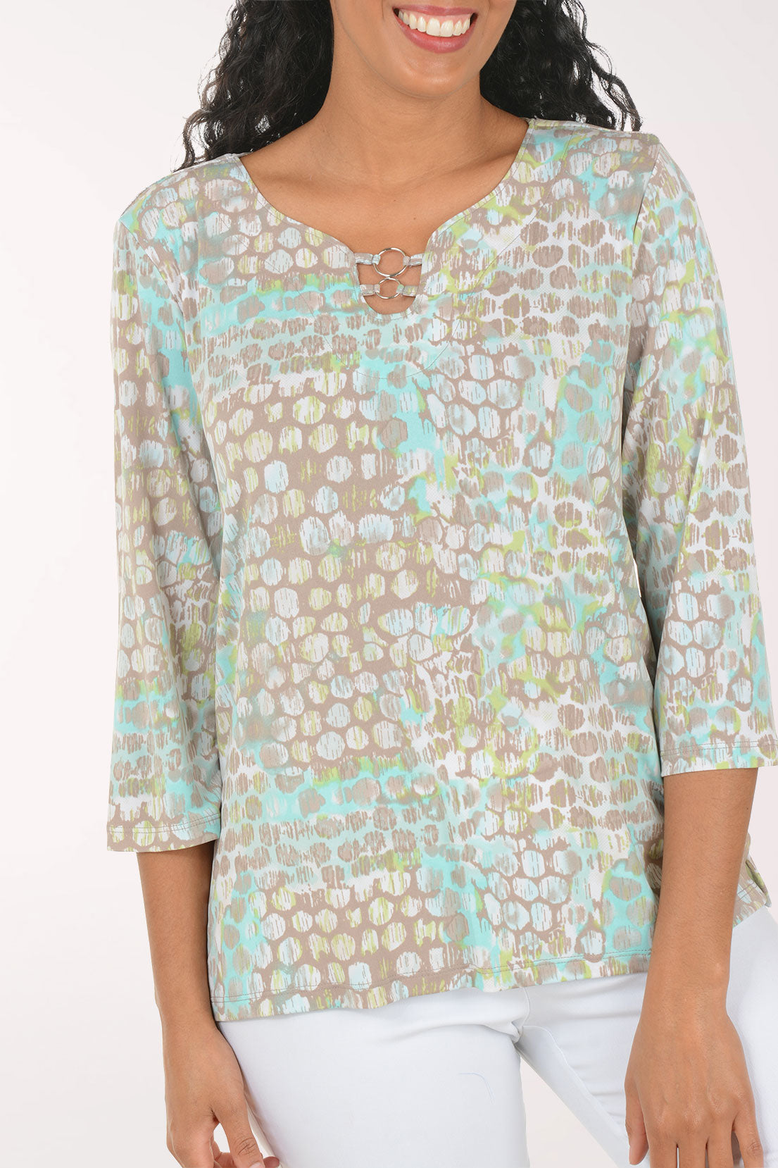 Woman wearing a floral blouse with white pants on a plain background