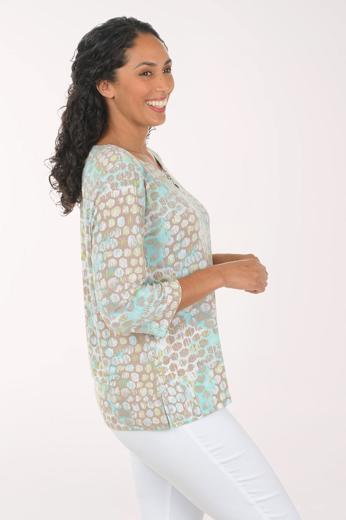 Woman wearing a floral blouse with white pants on a plain background