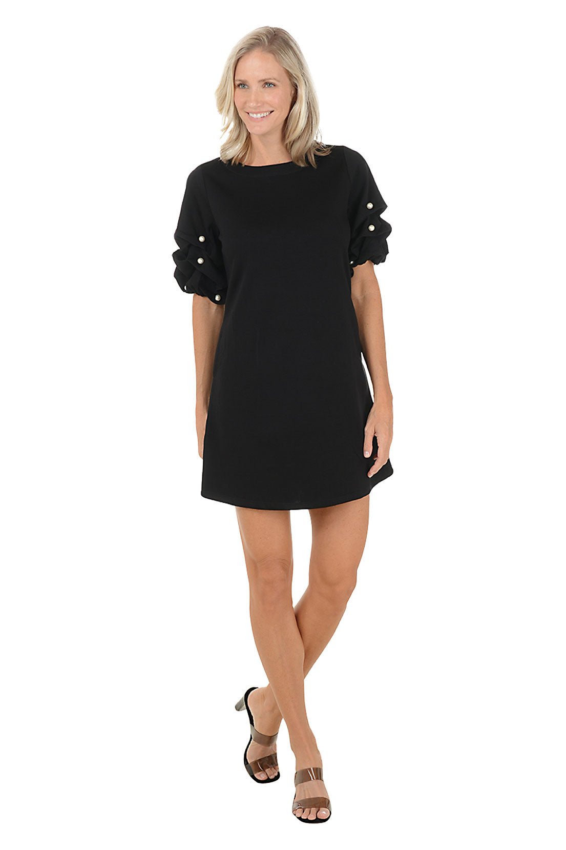 Woman wearing a black dress with pearl embellishments on a white background.