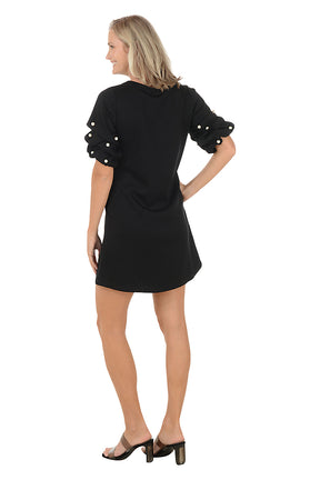 Woman wearing a black dress with pearl embellishments on a white background. Back shot.