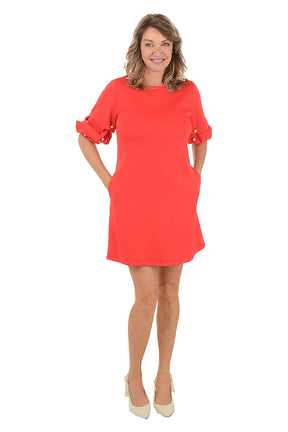 Woman wearing a red dress with pearl embellishments on a white background.