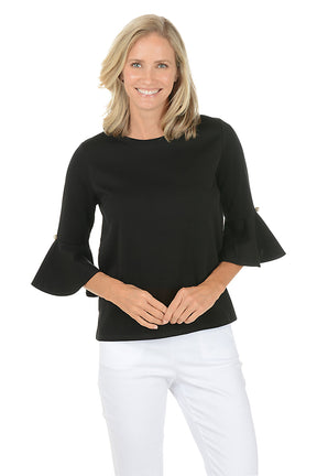 Woman wearing a black bell-sleeve top and white pants on a white background. Second front shot.