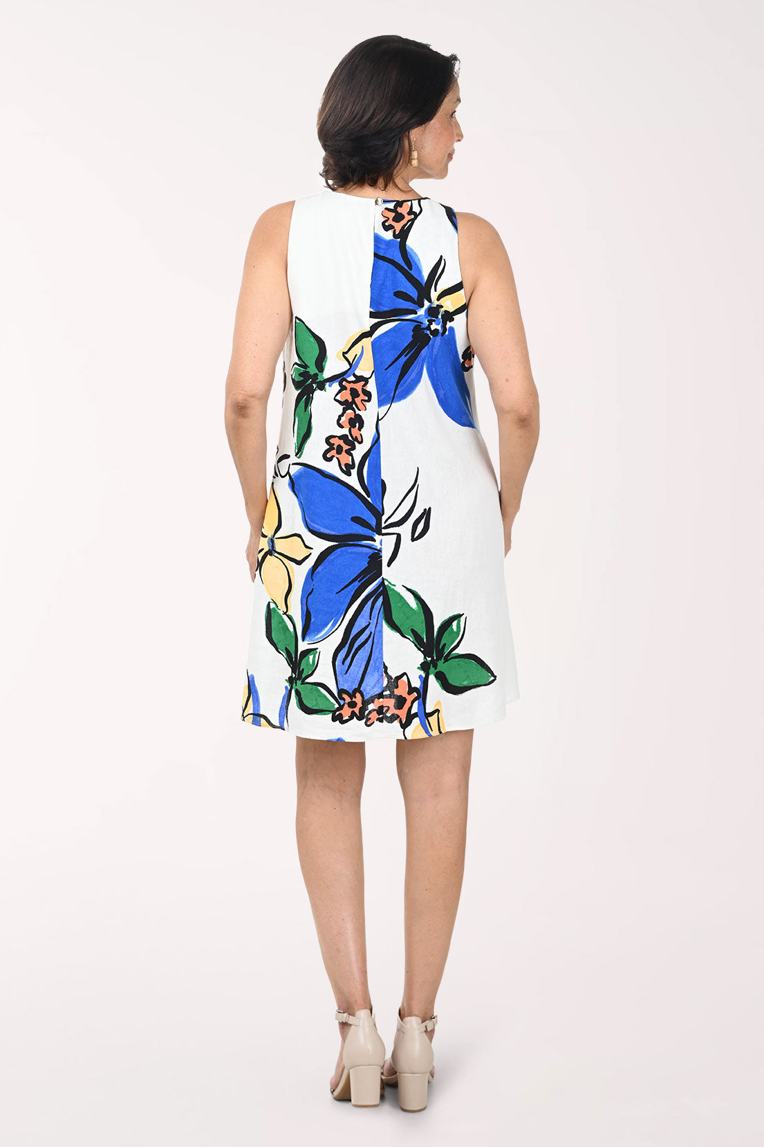 Woman wearing a floral dress with blue and yellow flowers on a white background