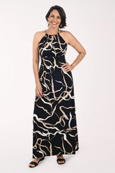 Woman wearing a black and beige patterned halter neck dress on a white background