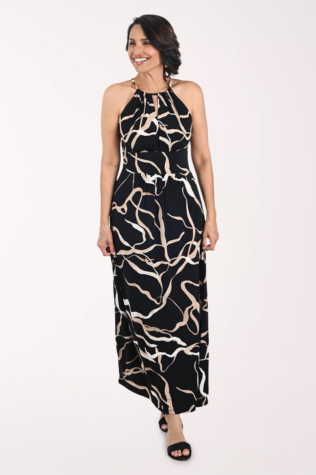 Woman wearing a black and beige patterned halter neck dress on a white background