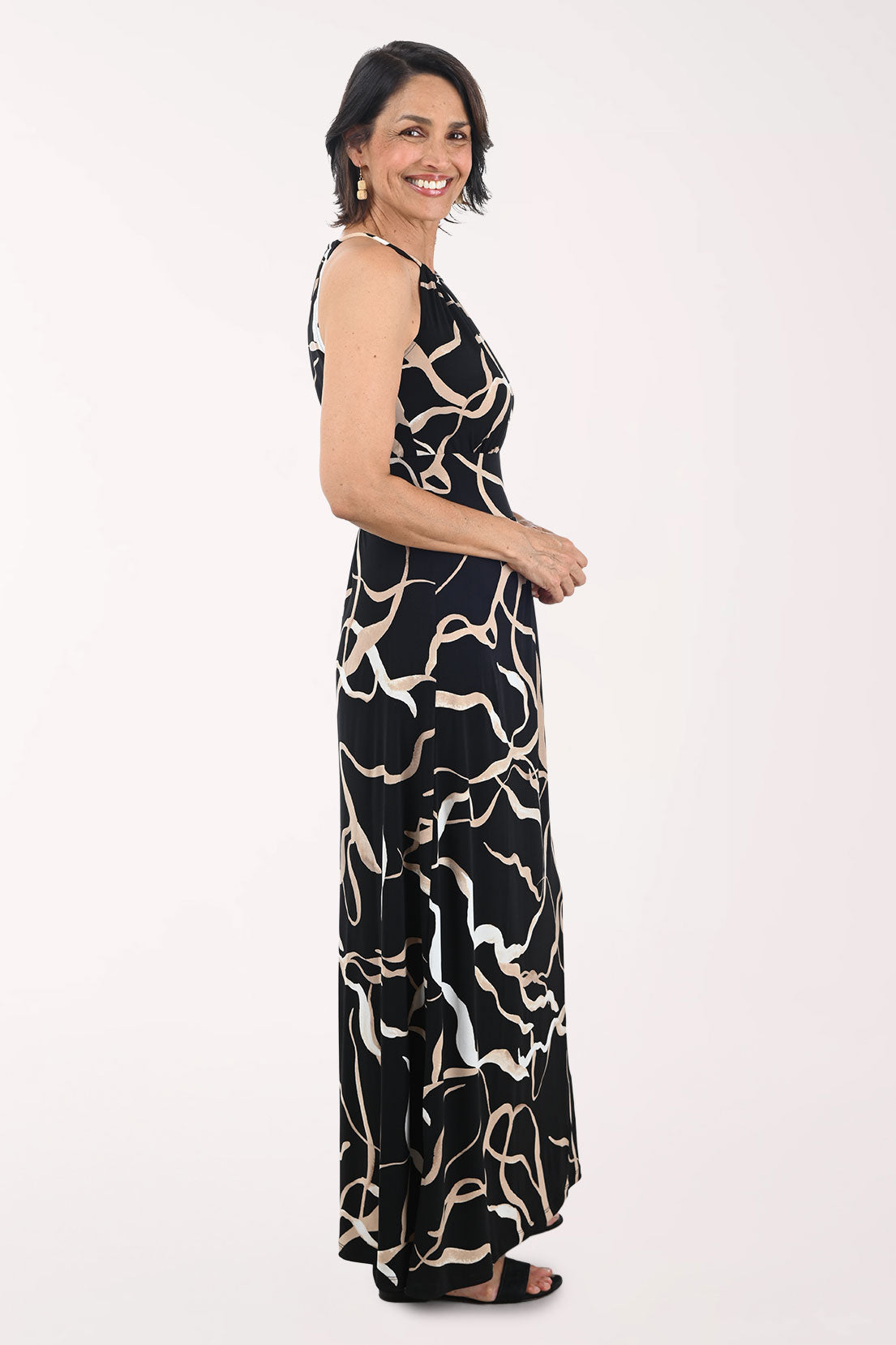 Woman wearing a black and beige patterned halter neck dress on a white background