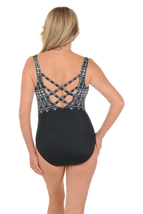 Woman wearing a black and white patterned swimsuit on a white background. Back shot.