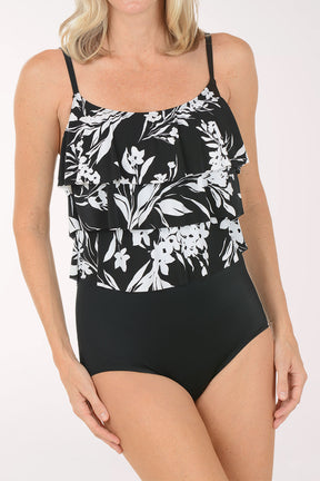 Woman wearing a black swimsuit with white floral patterns on a white background