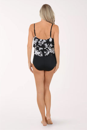 Woman wearing a black swimsuit with white floral patterns on a white background