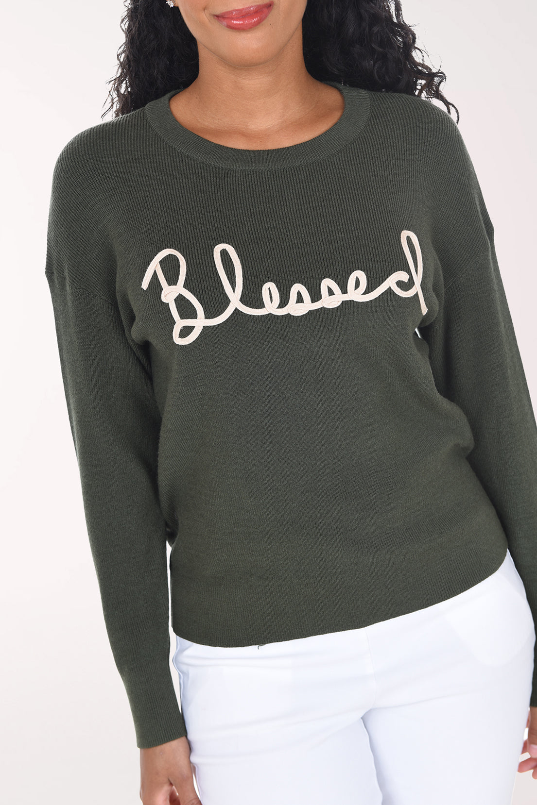 Close-up of the olive green rib knit showing the cream soutache "Blessed" lettering and crew neckline.