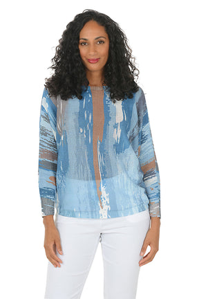 Woman wearing a blue patterned blouse with sheer panels on a white background.