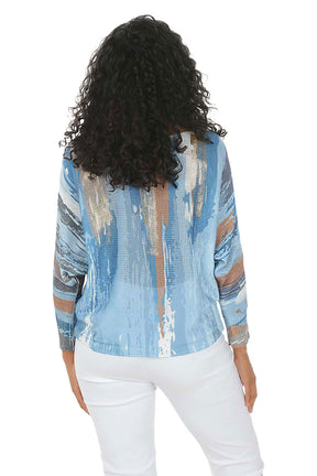 Woman wearing a blue patterned blouse with sheer panels on a white background. Back shot.