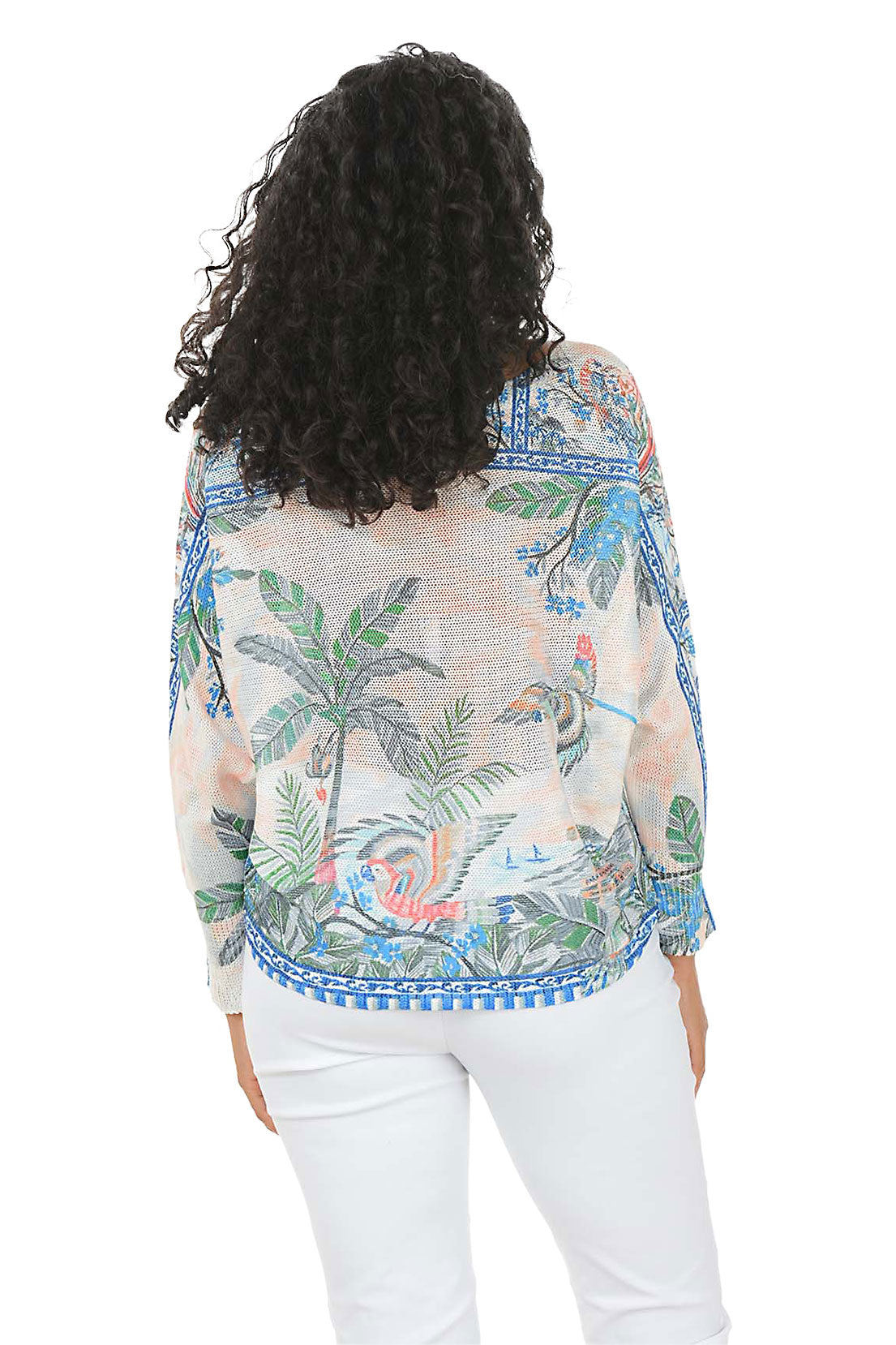 Woman wearing a tropical patterned blouse with palm trees and flowers on a white background. Back shot.