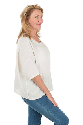 Woman wearing a white blouse and blue pants on a white background. Side shot.