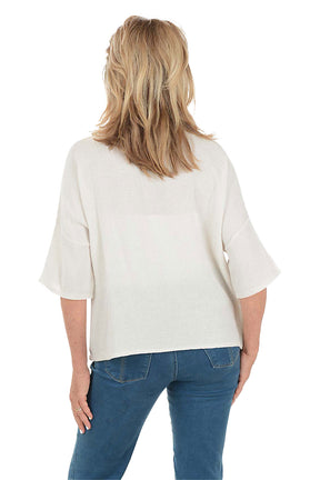 Woman wearing a white blouse and blue pants on a white background. Back shot.