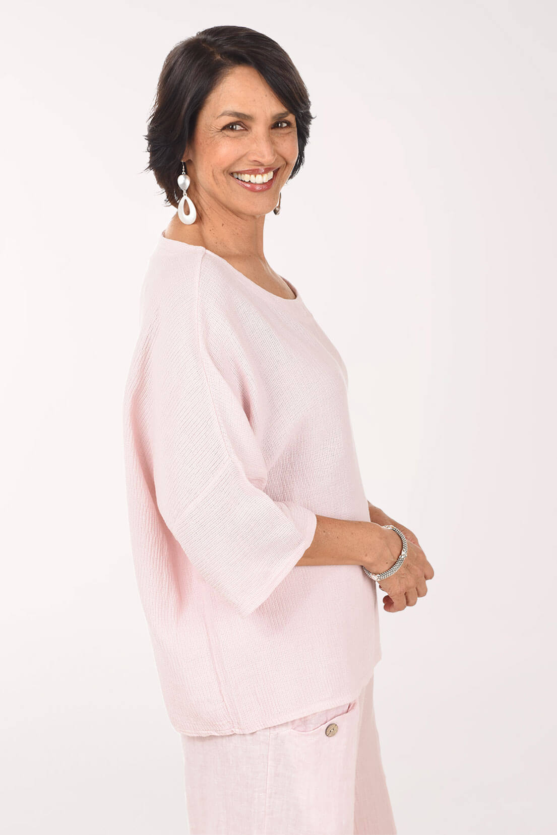 Woman wearing a light pink outfit on a white background - side shot