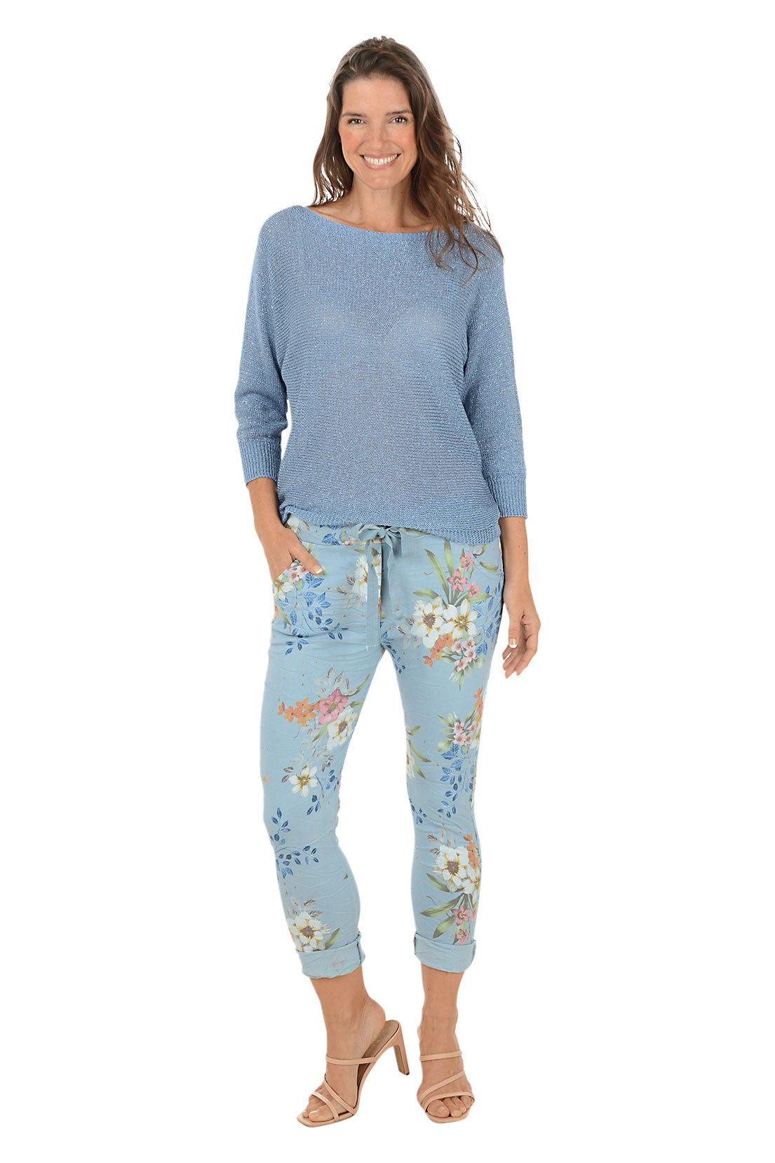 Woman wearing a blue sweater and floral pants on a white background