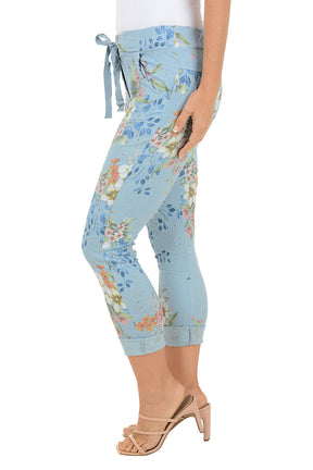 Light blue capri pants with floral pattern worn by a person on a white background. Side shot.