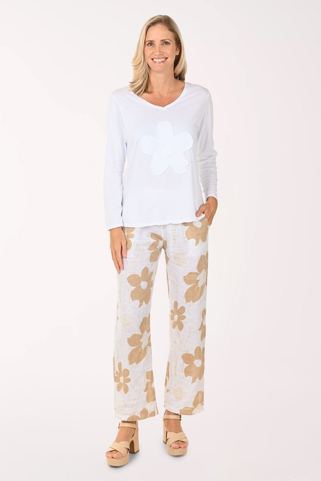 Woman wearing a white top and floral pants on a white background