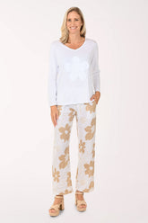 Woman wearing a white top and floral pants on a white background