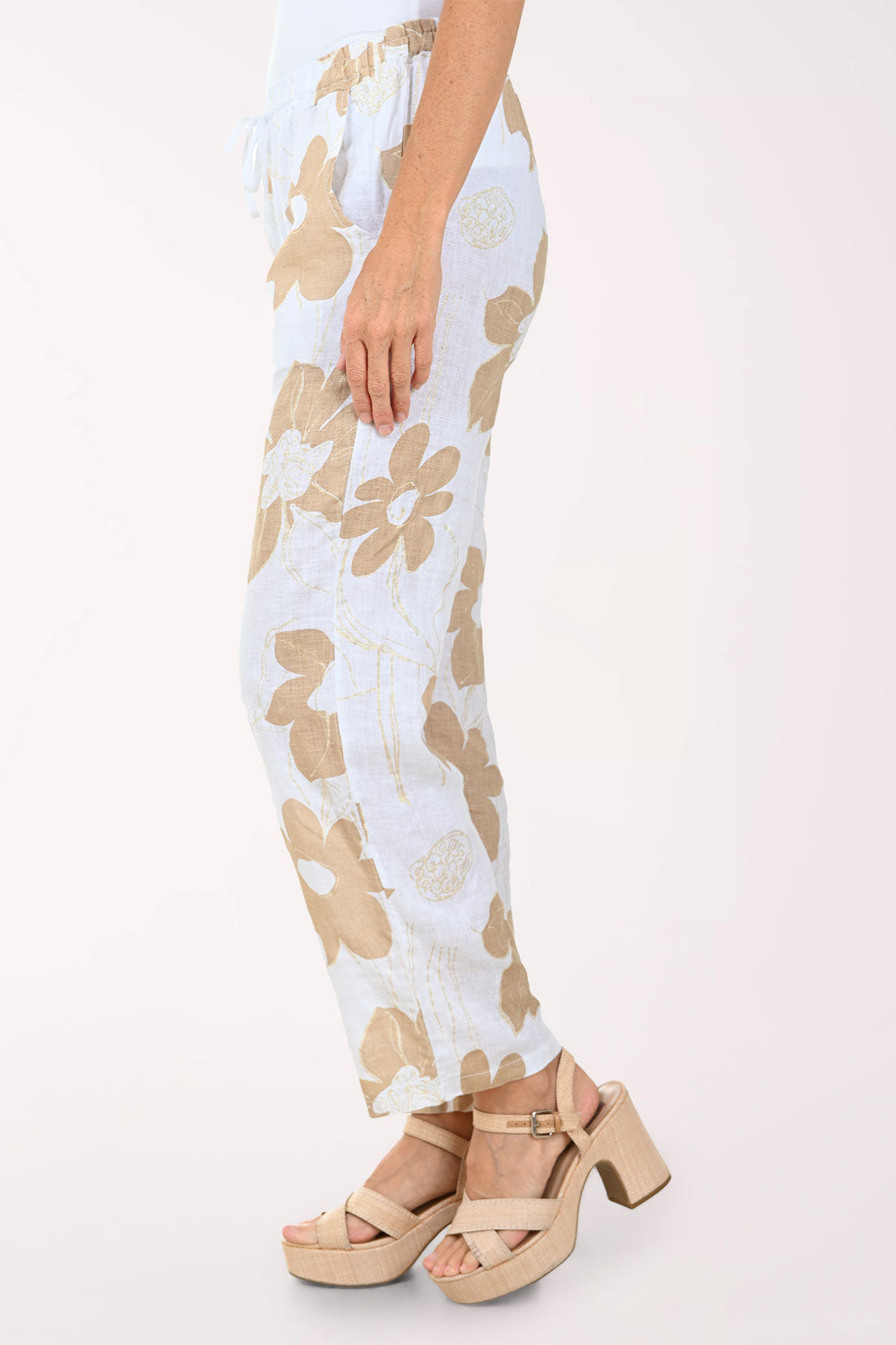 Woman wearing a white top and floral pants on a white background