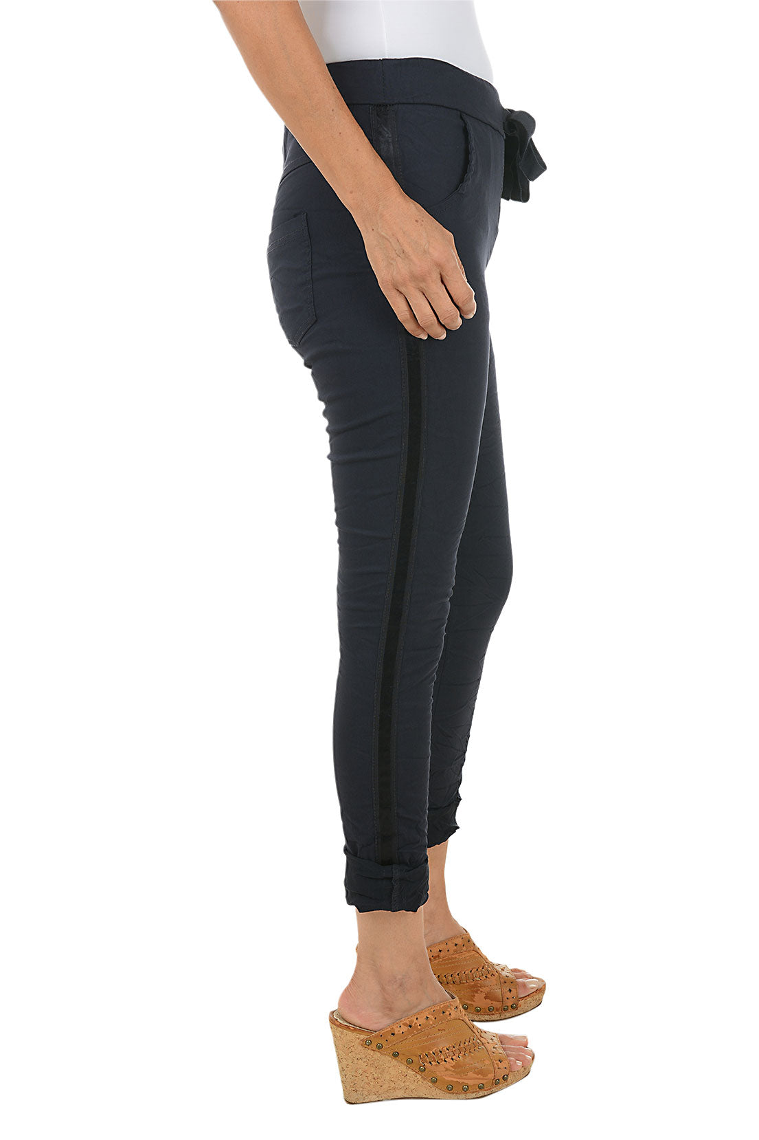 Person wearing navy jogger pants with a stripe on the side on a white background. Side shot.